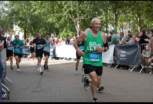 Runner in a green race vest leading a crowded city 10k