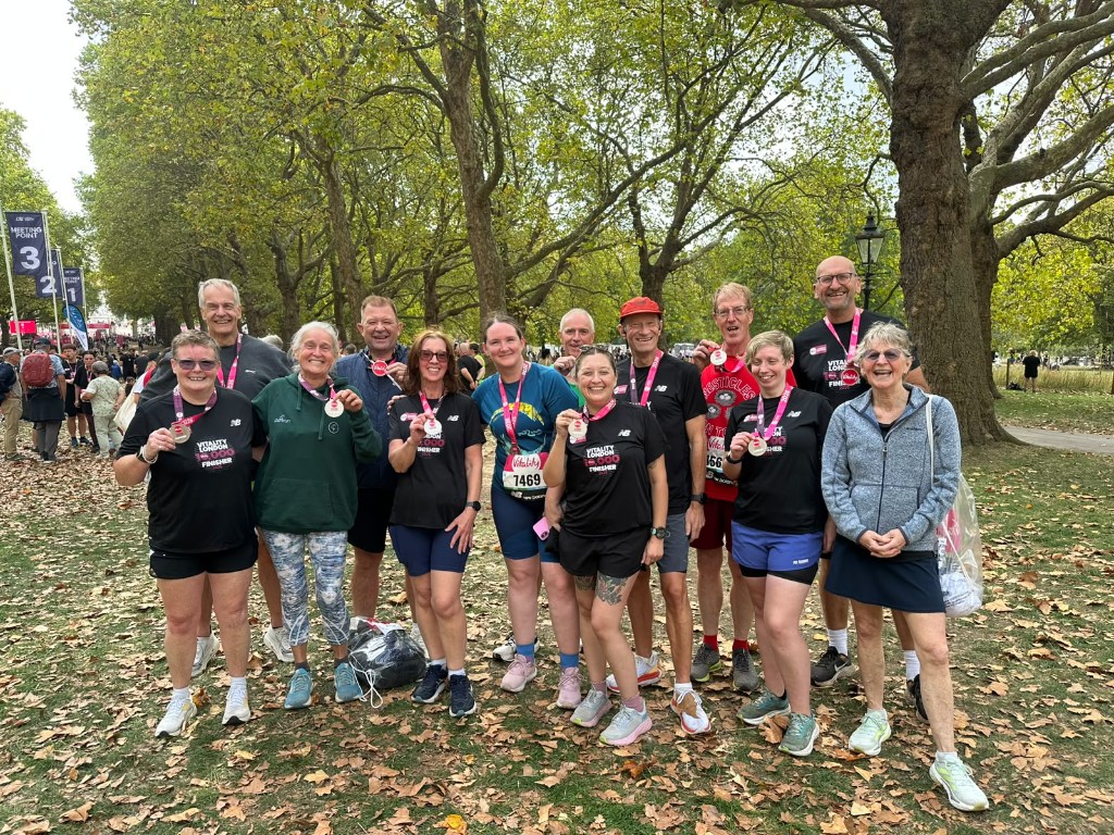 Club runners holding Vitality 10,000 finisher medals in Hyde Park